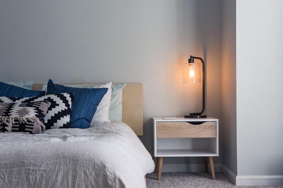 Dormitorio sereno con ropa de cama de lino color crema, cabecero tapizado y luz cálida