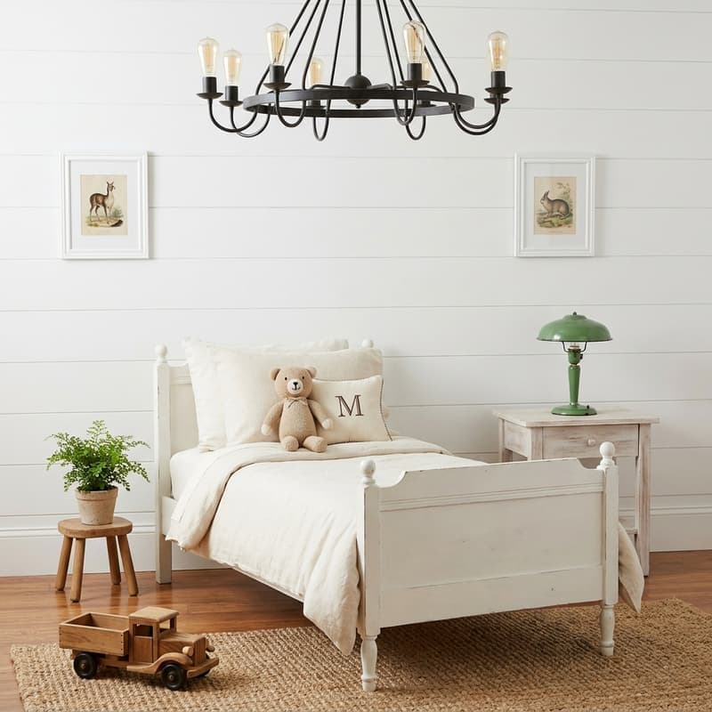 Habitación rústica farmhouse infantil con cama vintage blanca, shiplap blanco, lámpara de hierro con Edison, juguete de madera y letra M bordada